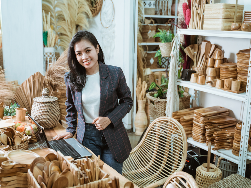 Business owner using managed services for handcrafted product sales, surrounded by wooden home decor items in a small shop.